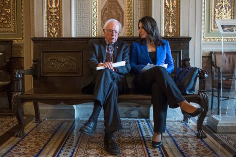In May 2017, Gabbard and Sanders sit in the Capitol's Senate Reception Room before a news conference introducing legislation that would incrementally raise the nation's minimum wage to  an hour.