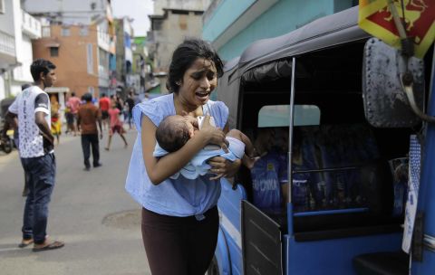 A woman carrying an infant runs for safety after police found a suspicious vehicle parked in Colombo, Sri Lanka, on Monday, April 22, a day after several coordinated bombings across the country killed hundreds.