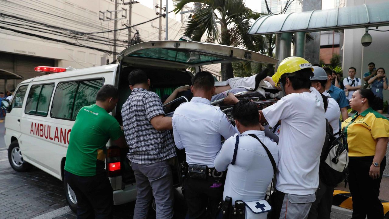 Workers carry an employee to an ambulance after she became dizzy when the earthquake hit Manila.