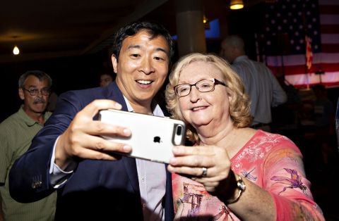 In August 2018, Yang takes a selfie with an attendee of the Democratic Wing Ding event in Iowa.
