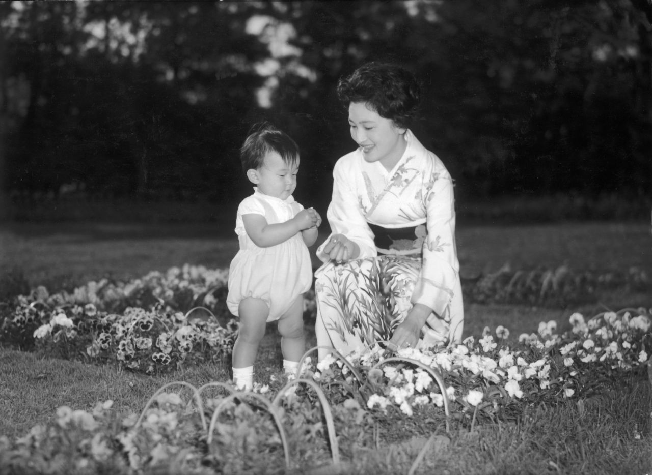 Michiko plays with 2-year-old Naruhito in the gardens of the Togu Royal Palace in May 1961.