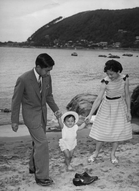 Naruhito walks with his parents on a beach at the Hayama Imperial Villa in June 1961.