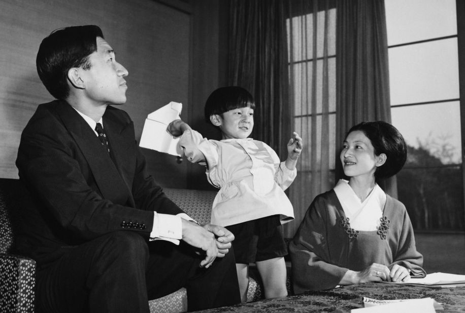 Naruhito throws a paper airplane with his parents in October 1965.