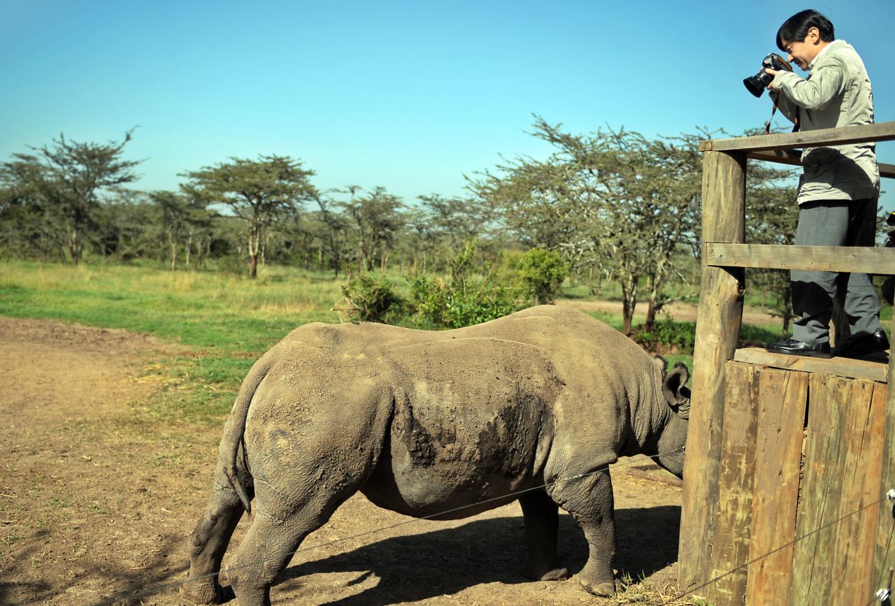 Naruhito takes a photo of a rhinoceros while touring a reserve in Kenya in March 2010.