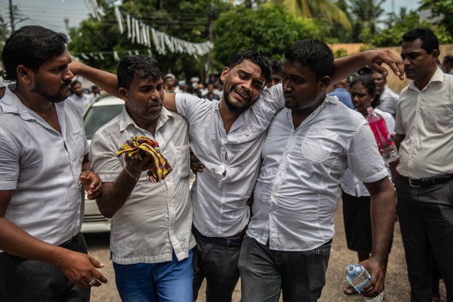 A man is supported as he follows a coffin during a mass funeral for bombing victims at St. Sebastian Church in Negombo, Sri Lanka, on Tuesday, April 23.