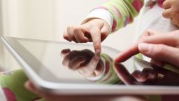 Close-up of a toddler and mother using a touch screen tablet.