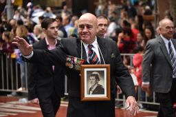 The relative of a fallen serviceman waves to crowds during the Anzac Day parade in Sydney on April 25, 2018.