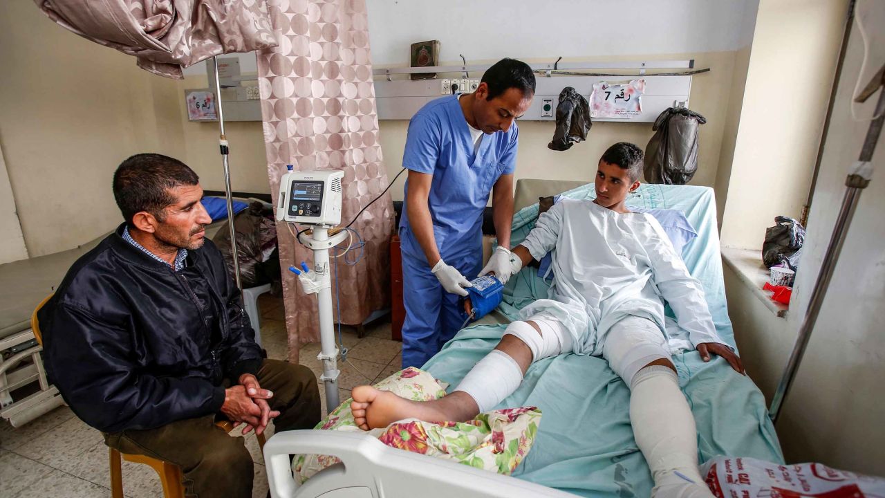 Al-Badan (right) receives treatment at Beit Jala Hospital near Bethlehem, as his father (left) looks on.
