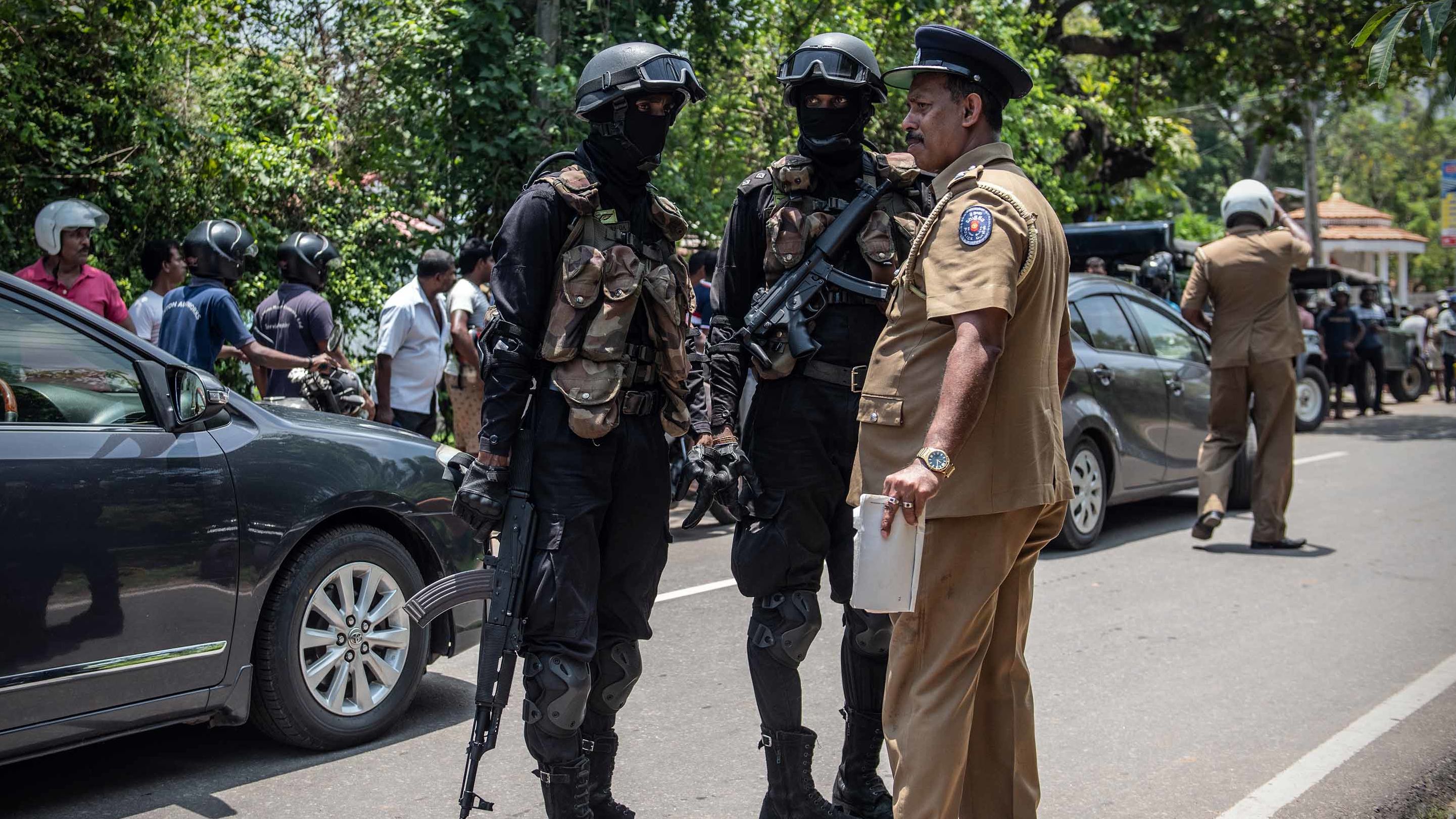 Military personnel talk with a police officer near the site where a package, believed to be a bomb, was detonated in a controlled explosion after being discovered in a nearby restaurant in Negombo on Wednesday, April 24.