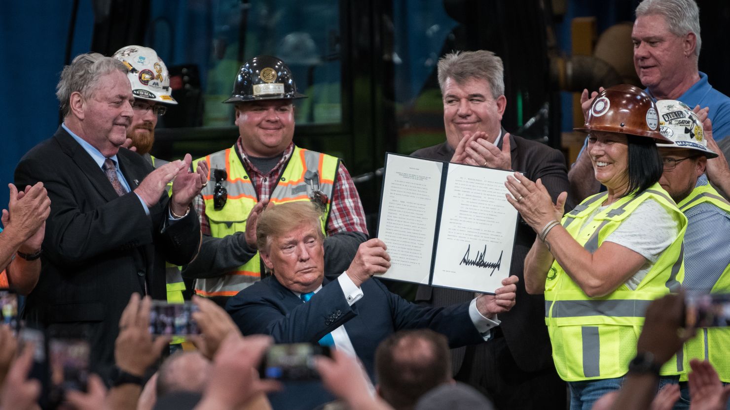 U.S. President Trump, seated, displays a signed executive order during an event at the International Union of Operating Engineers (IUOE) Training and Education Center in Crosby, Texas, U.S., on Wednesday, April 10, 2019. Photographer: Loren Elliott/Bloomberg via Getty Images