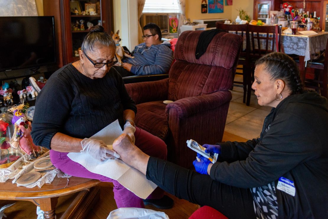 Patricia Zamora's grandmother helps clean her wound. Zamora had to stop working, was evicted and eventually moved into her grandmother's house.