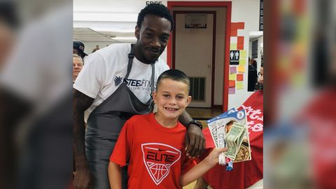 Connor holding his earnings after reading a book to his barber and friend Jerry Jones.