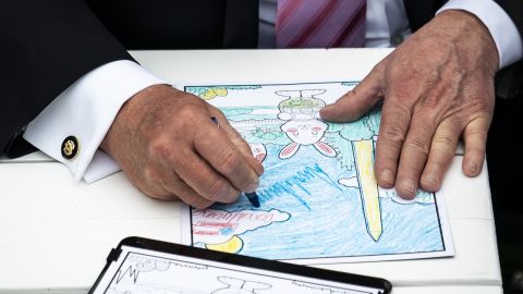US President Donald Trump signs a child's coloring book during the White House's annual Easter Egg Roll on Monday, April 22.