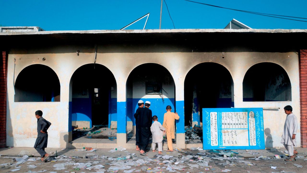 In this picture taken on Monday outside Peshawar, Pakistani children look at a damaged health center local torched by a mob following rumors related to polio vaccinations.