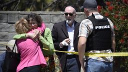 Two people hug as another talks to a San Diego County Sheriff's deputy outside of the Chabad of Poway Synagogue Saturday, April 27, 2019, in Poway, Calif. Several people have been shot and injured at a synagogue in San Diego, California, on Saturday, said San Diego County authorities. (AP Photo/Denis Poroy)