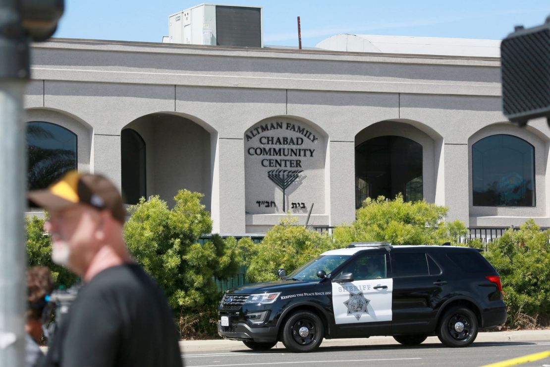 Neighborhood residents and members of the media stand before the Chabad of Poway Synagogue after the attack in Poway, California.