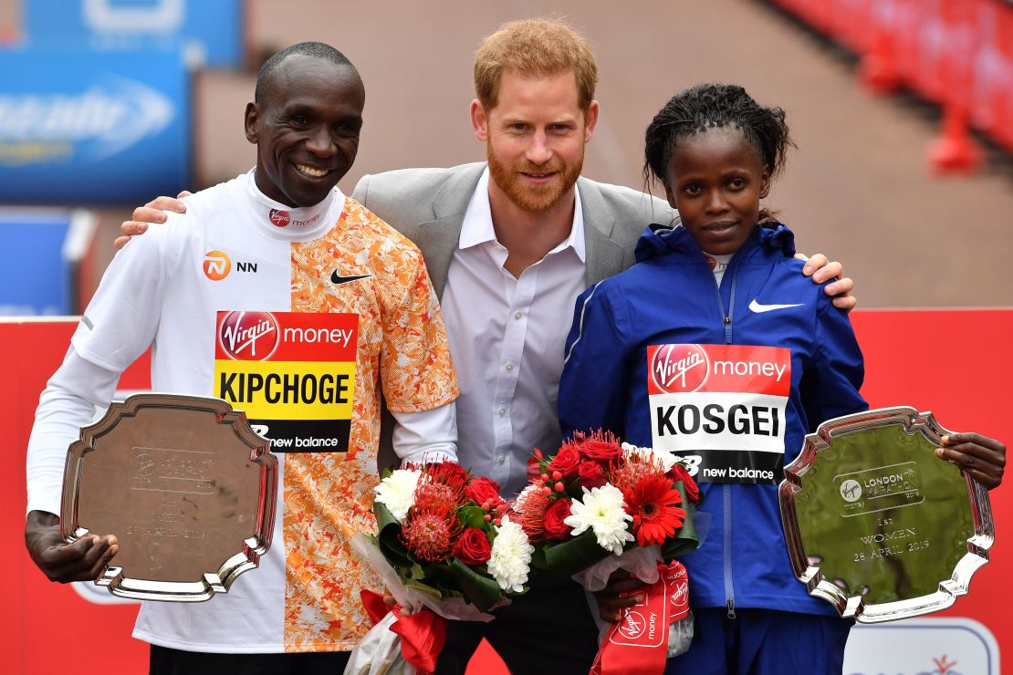 Britain's Prince Harry, Duke of Sussex, is flanked by men's race winner Kenya's Eliud Kipchoge (L) and women's race winner, Kenya's Brigid Kosgei (R) at the medal ceremony at the 2019 London Marathon.
