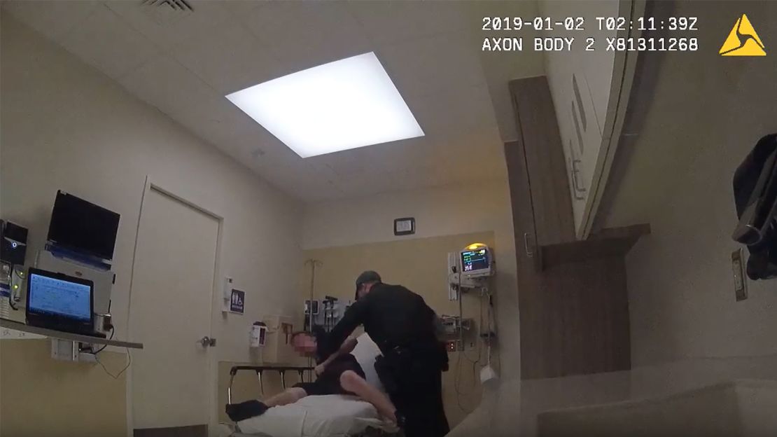 A Broward sheriff's deputy tries to restrain a suspect who is handcuffed to a hospital bed.