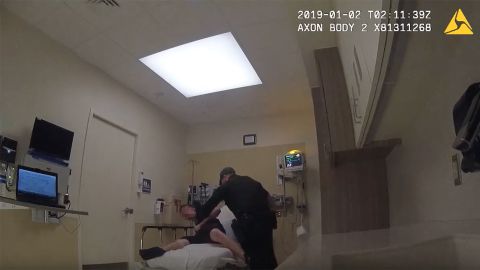 A Broward sheriff's deputy tries to restrain a suspect who is handcuffed to a hospital bed.