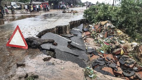 Residents stand next to a road partially destroyed by floods after heavy downpours in the Mozambican city of Pemba Sunday.