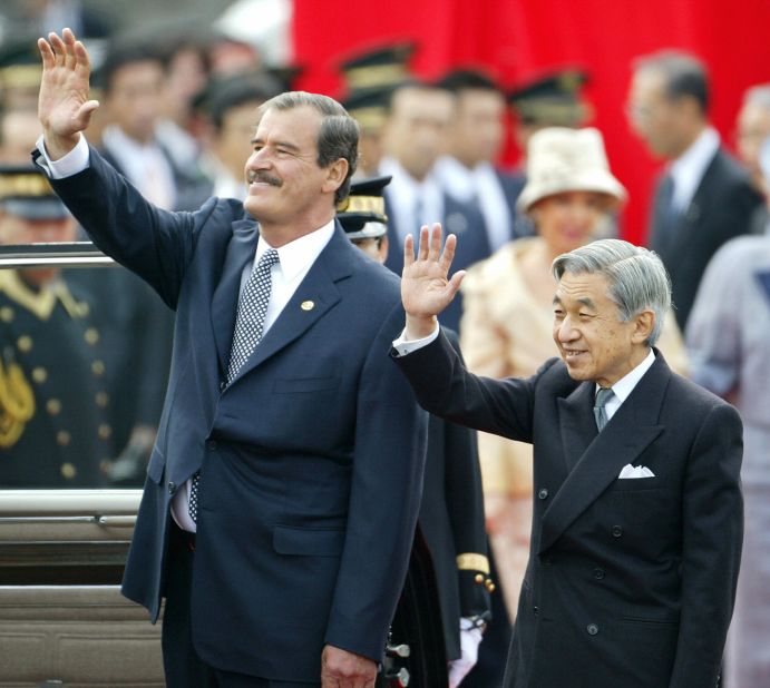 Akihito and Mexican President Vicente Fox wave to people while Fox visited Tokyo in 2003.