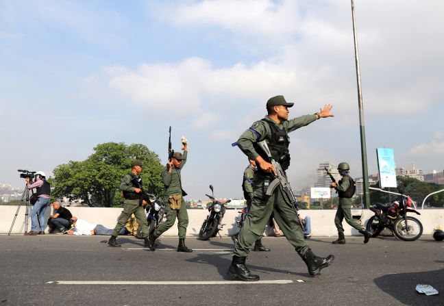 Military members gesture near the airbase. The blue armbands were worn in solidarity to the opposition.