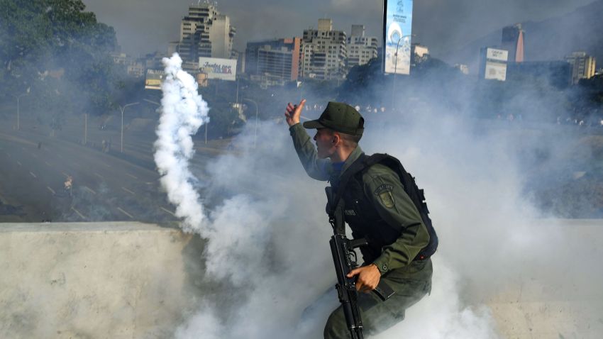 TOPSHOT - A member of the Bolivarian National Guard supporting Venezuelan opposition leader and self-proclaimed acting president Juan Guaido throws a tear gas canister during a confrontation with guards loyal to President Nicolas Maduro's government in front of La Carlota military base in Caracason April 30, 2019. - Guaido said on Tuesday that troops had joined his campaign to oust President Nicolas Maduro as the government vowed to put down what it called an attempted coup. (Photo by Yuri CORTEZ / AFP)        (Photo credit should read YURI CORTEZ/AFP/Getty Images)