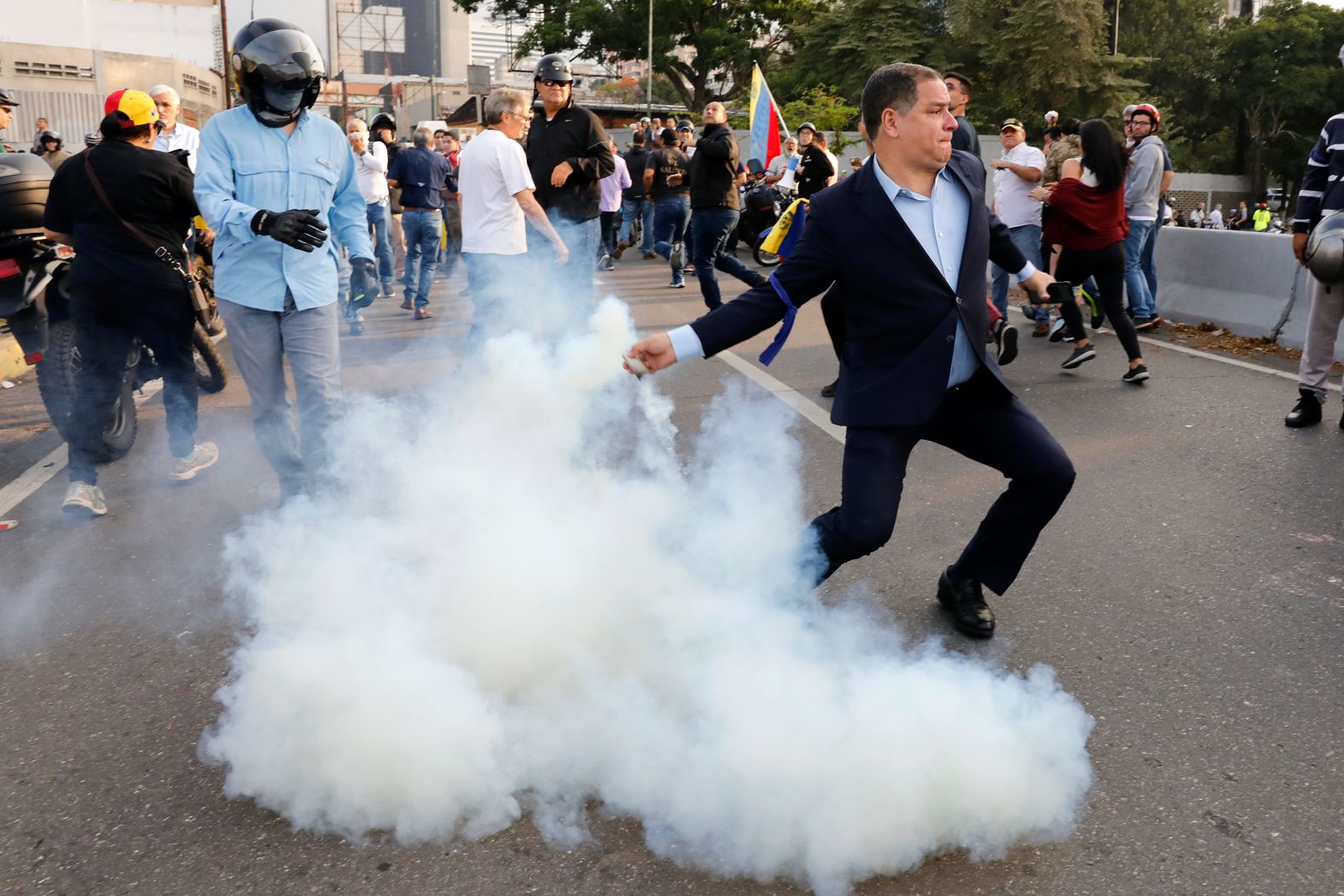 A person opposed to the Maduro government returns a tear-gas canister to the pro-Maduro soldiers who launched it.