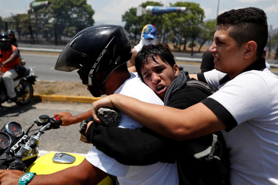 Opposition demonstrators help an injured man near the airbase.