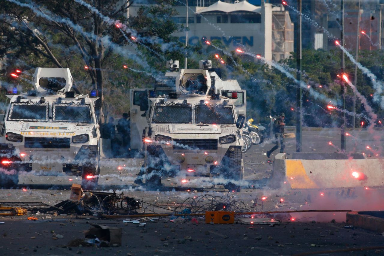 Fireworks launched by Maduro opponents land near National Guard armored vehicles.