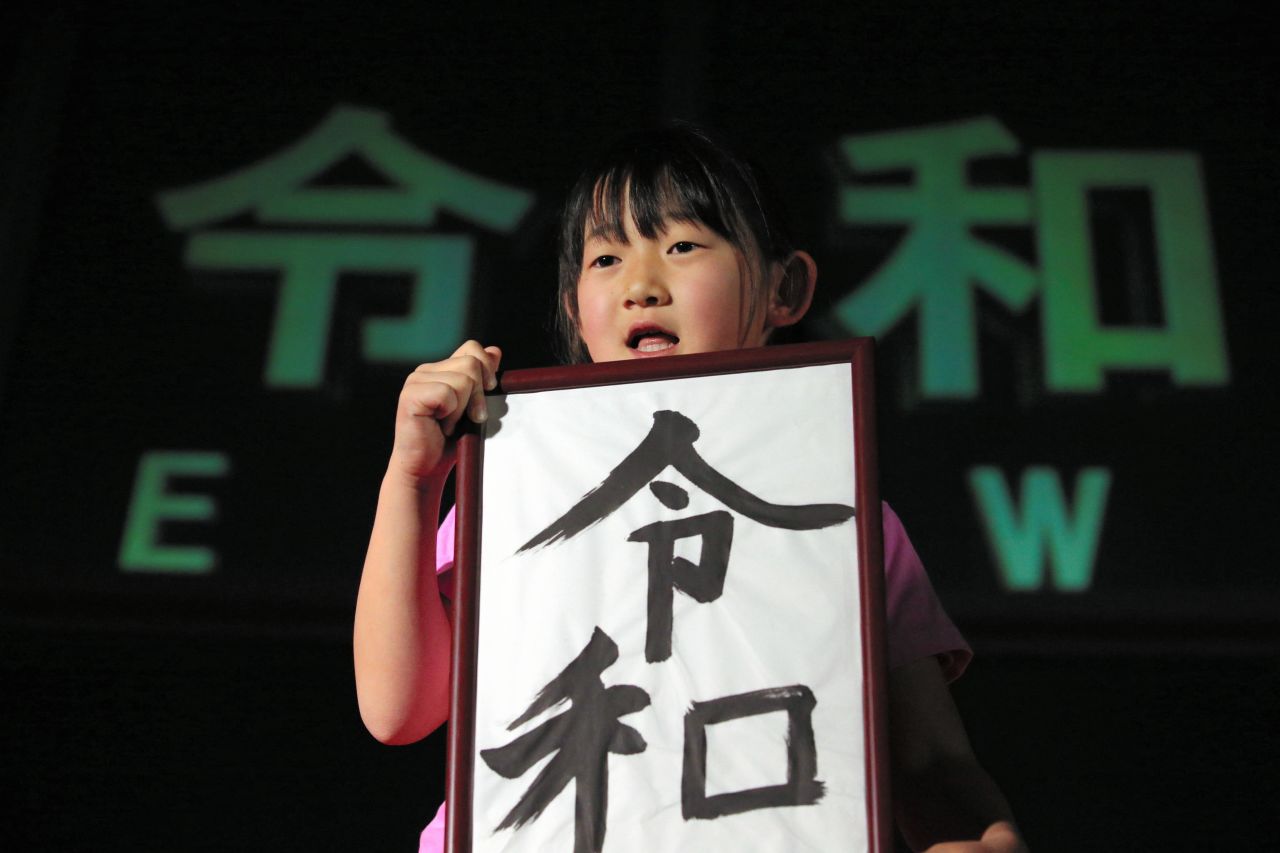 A girl holds calligraphy reading "Reiwa," the name of the new imperial era. 