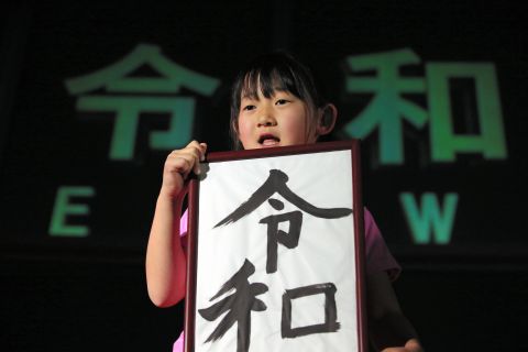 A girl holds calligraphy reading "Reiwa," the name of the new imperial era. 