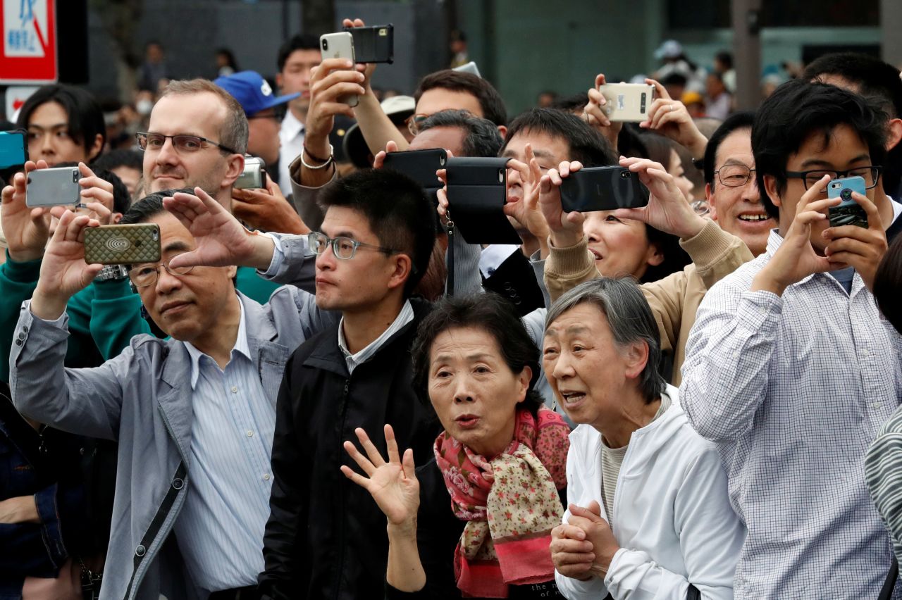 People take pictures as the royal family leaves the Imperial Palace.
