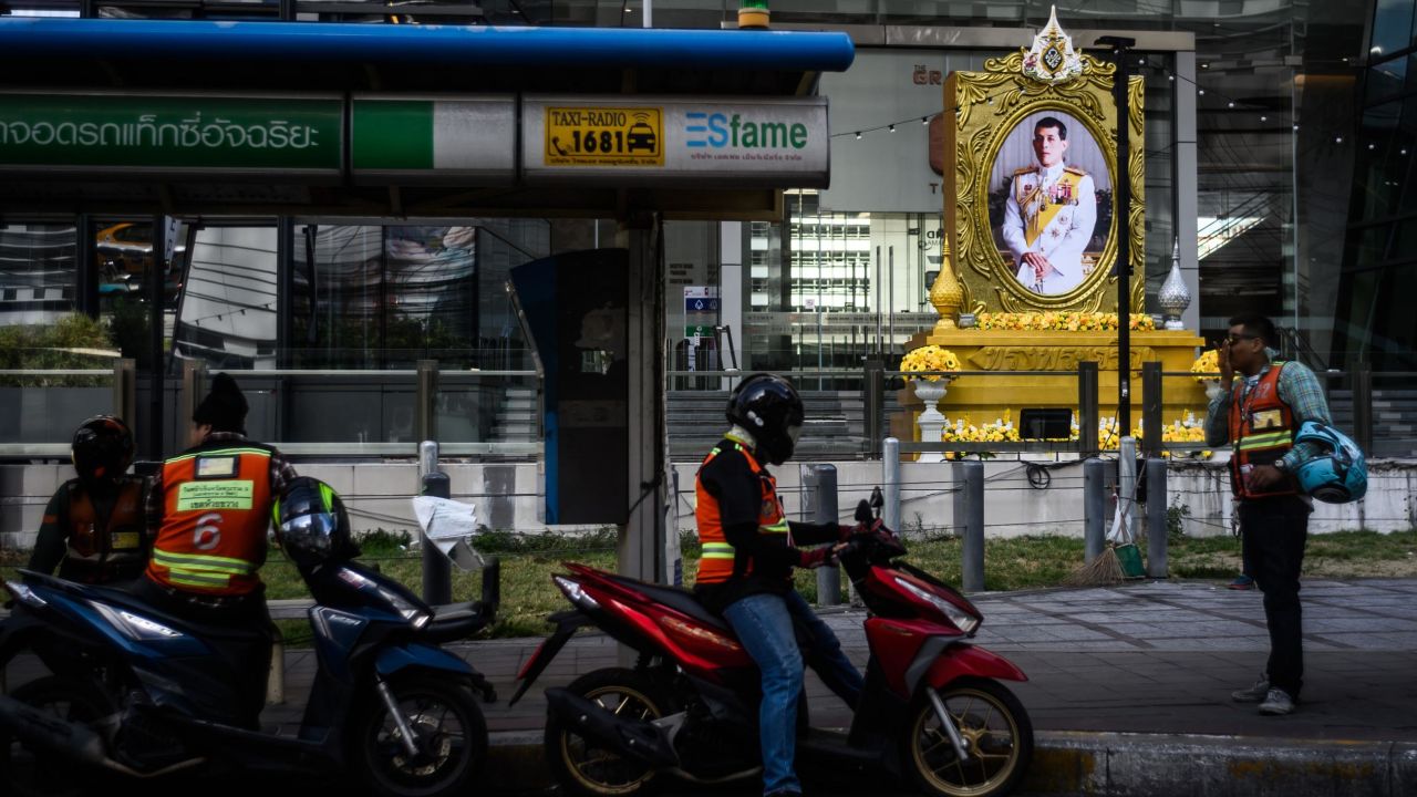 Motorbike taxi drivers wait for passengers near a portrait of Thailand's King Maha Vajiralongkorn in Bangkok on Wednesday.