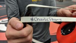 Luke Peterson holds up #charliestrong headgear before a meet