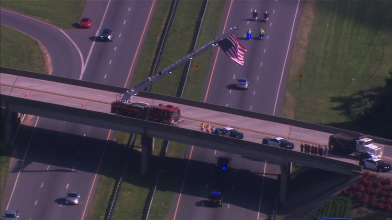 A vehicle carrying Howell's body back to his hometown Thursday, escorted by police, goes under an overpass where a fire crew raised a US flag in tribute.