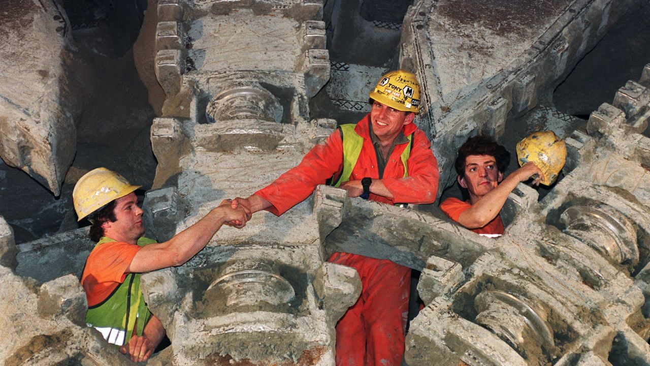 French and English workers shake hands after a giant drilling machine broke through the last section of the tunnel in 1991.