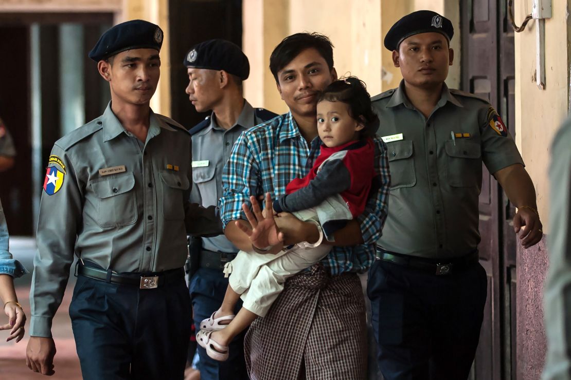 Detained Myanmar journalist Kyaw Soe Oo carrying his daughter is escorted by police for his ongoing trial at a court in Yangon on June 12, 2018.