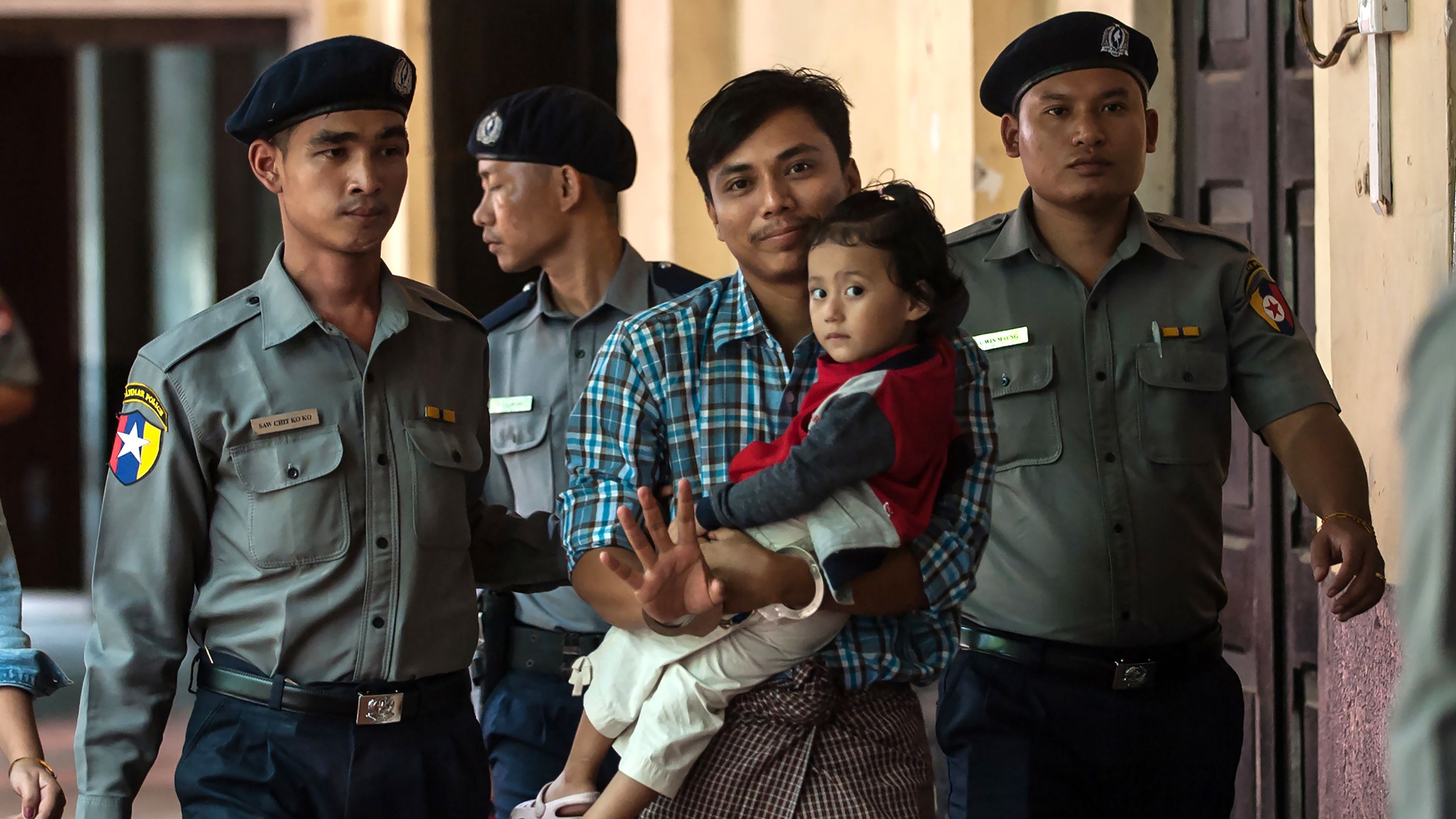 Detained Myanmar journalist Kyaw Soe Oo carrying his daughter is escorted by police for his ongoing trial at a court in Yangon on June 12, 2018.