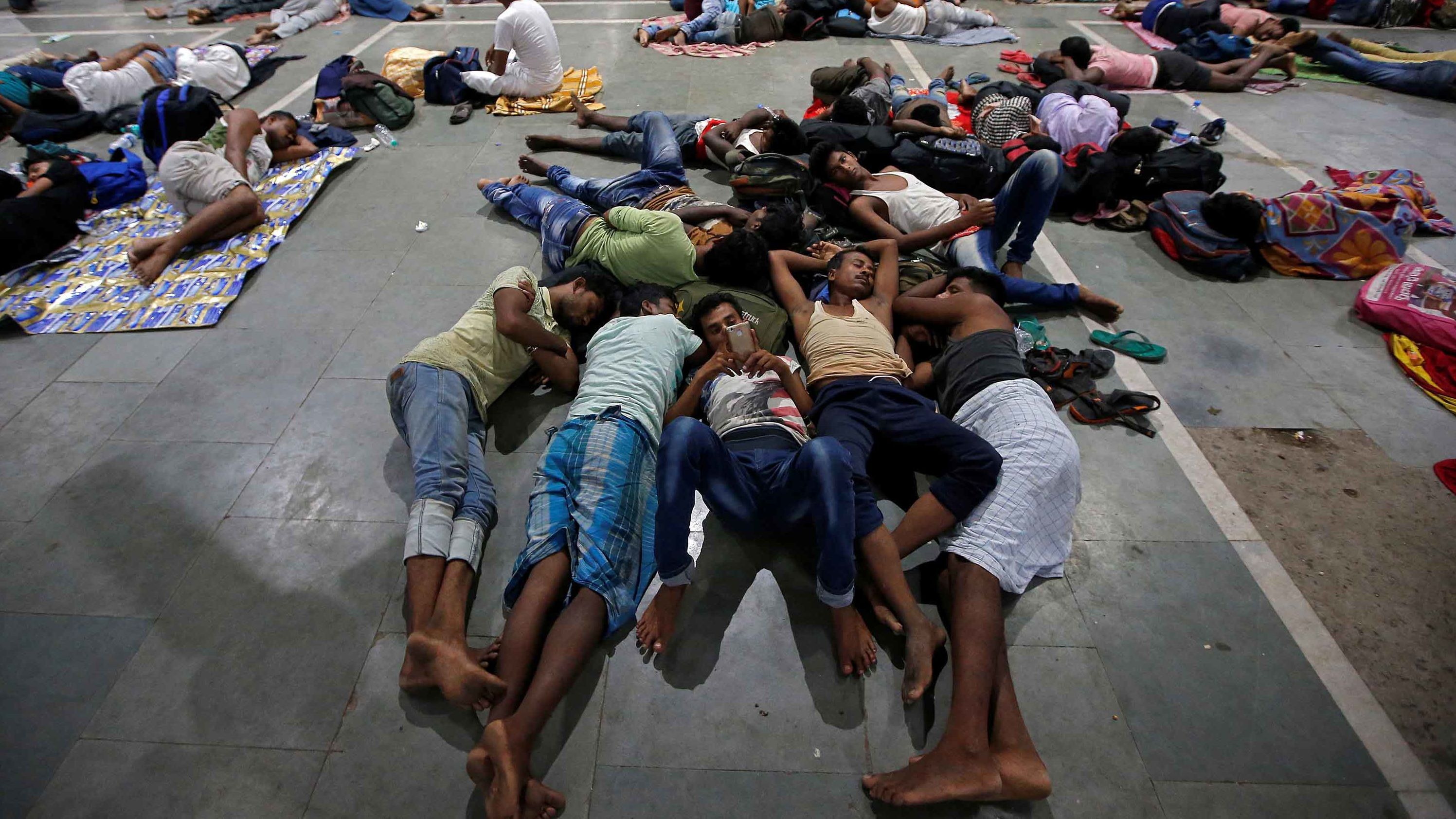 Stranded passengers rest inside a railway station in Kolkata after trains were canceled ahead of the storm.