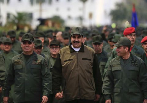 In this handout photo, released by the Miraflores Press Office, Venezuelan President Nicolas Maduro, center, is accompanied by military officers as he arrives for a meeting with troops at Caracas' Fort Tiuna on Thursday, May 2.