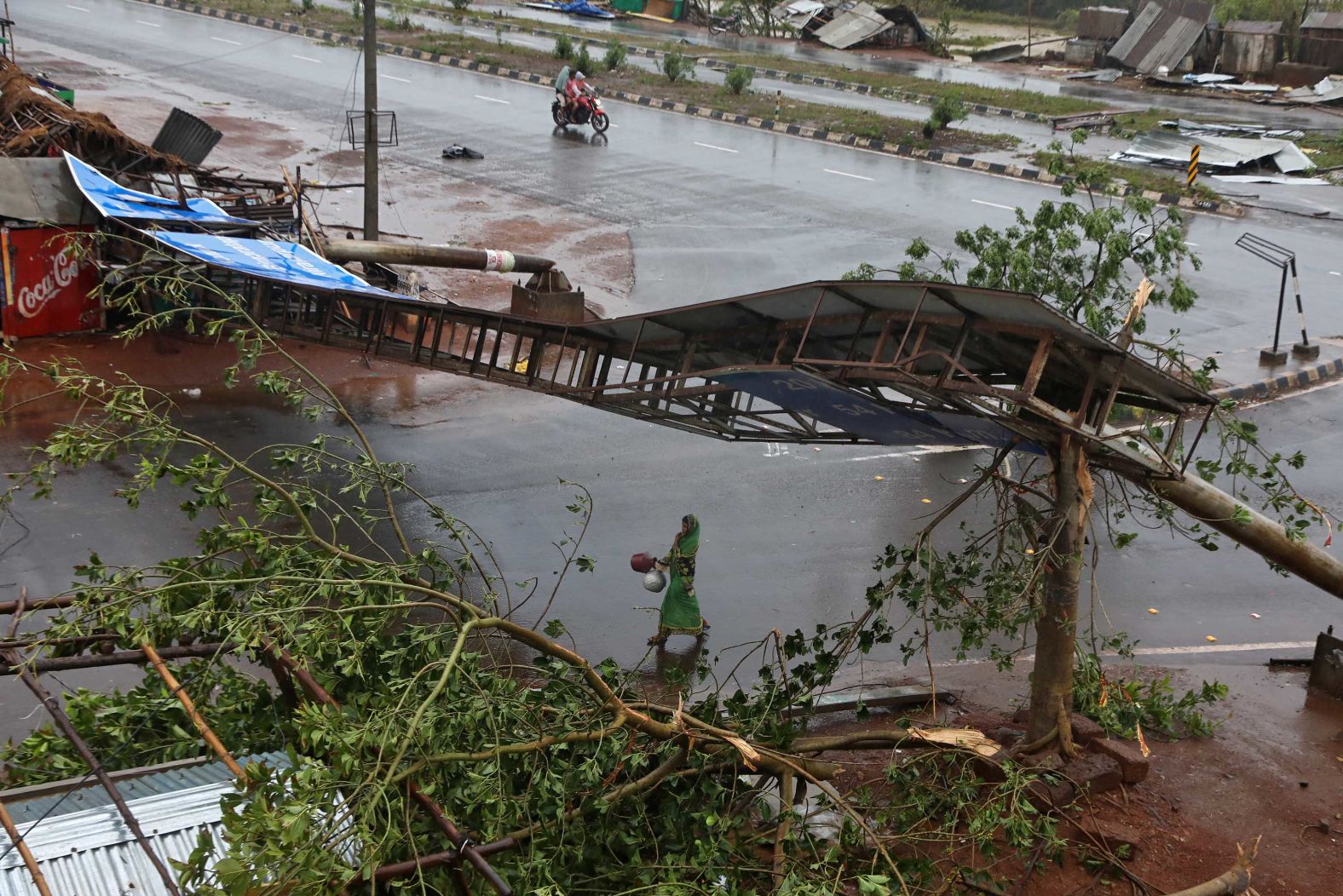 A woman walks amid fallen debris in India's Khordha district.