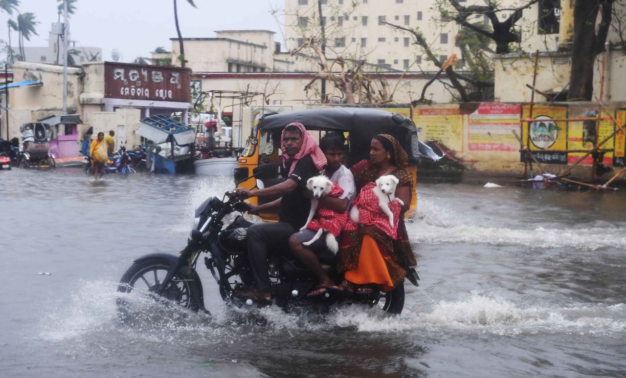 People ride along a flooded road in Puri on May 3.