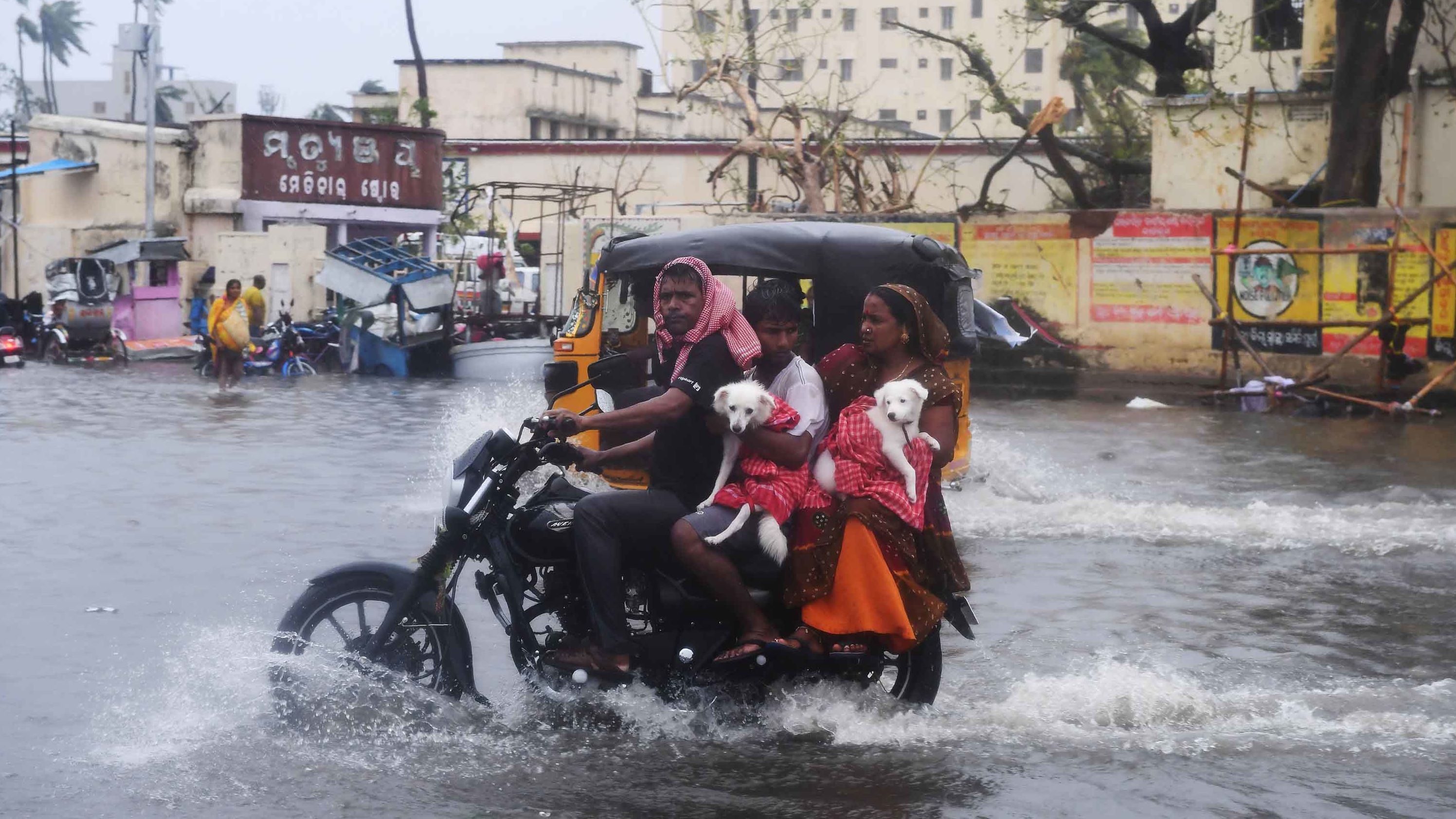 People ride along a flooded road in Puri on May 3.