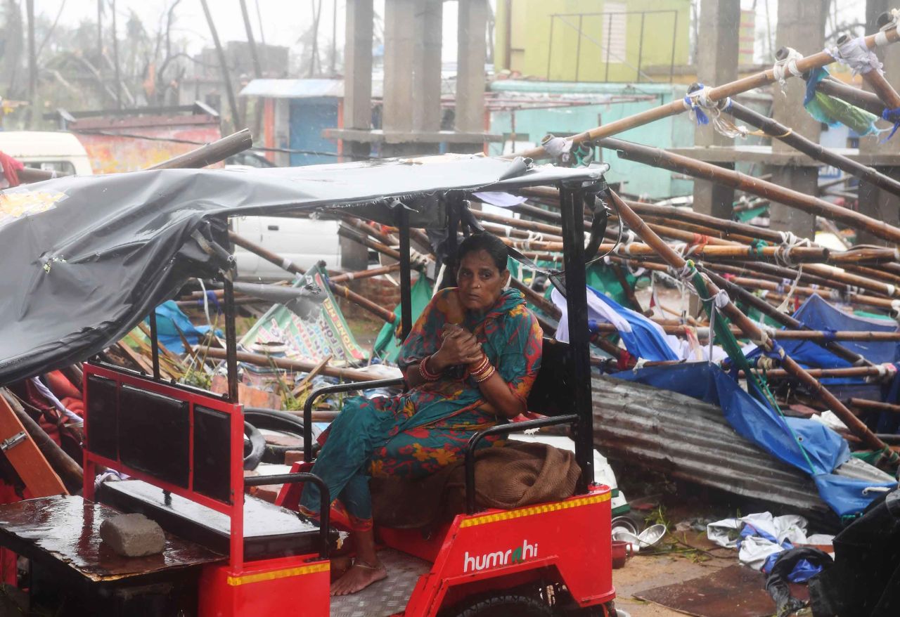 A woman sits on an electric rickshaw in the midst of a structure damaged by the storm.