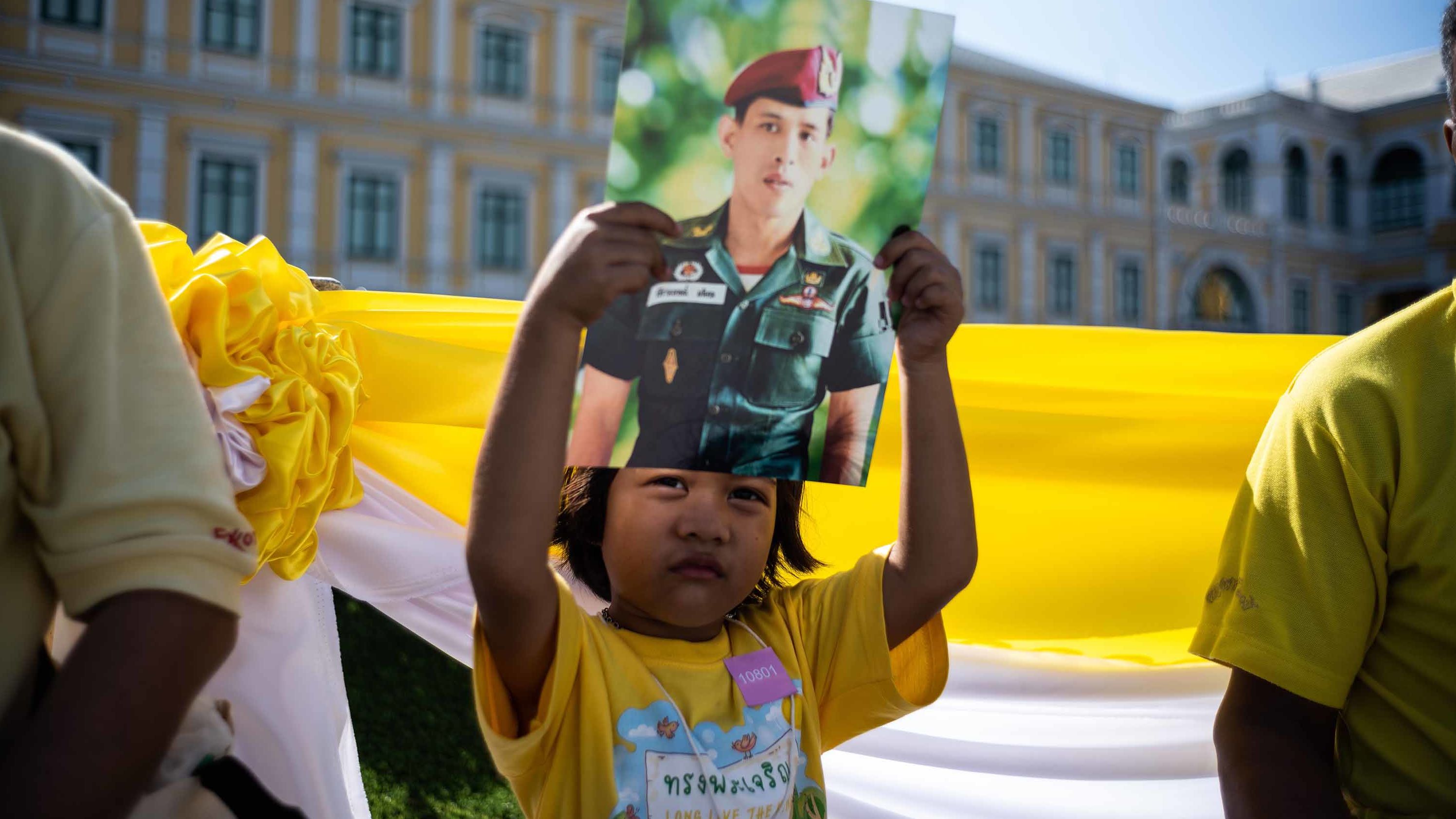 A child holds a portrait of King Vajiralongkorn as she waits with others near the Grand Palace during the coronation on May 4.