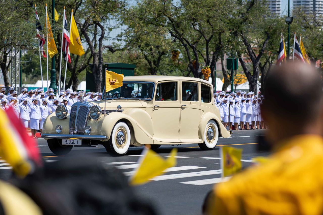 A car carrying King Maha Vajiralongkorn and Queen Suthida makes its way to the Grand Palace.