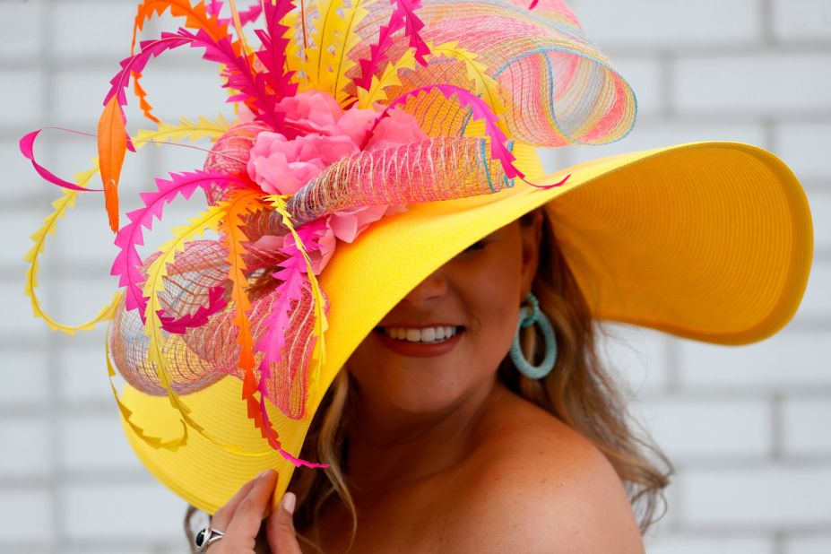 A woman shows off her pink and yellow hat.