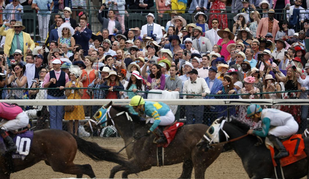 People cheer as they watch a race at Churchill Downs before the 145th running of the Kentucky Derby.