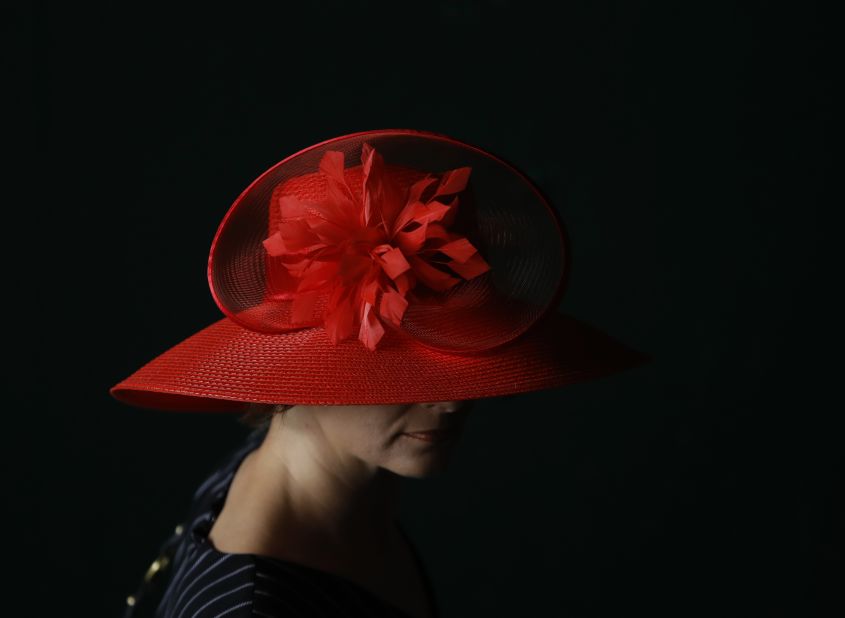 A woman wears a red hat before the Kentucky Derby.
